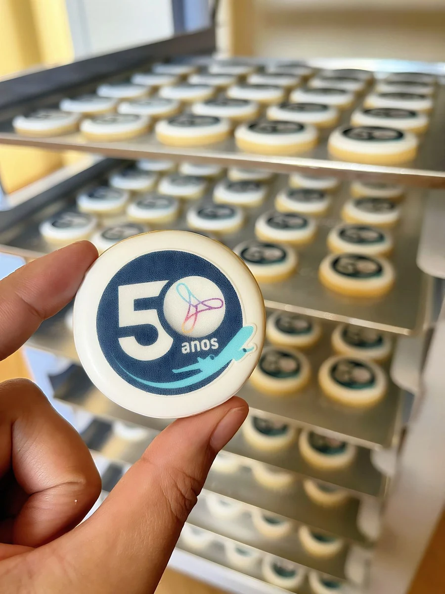 Biscoito comemorativo de 50 anos da Rextur Advance, com peças em produção ao fundo