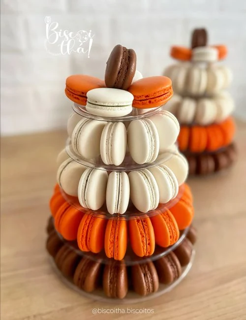 Macarons brancos, laranja e chocolate organizados em uma torre de confeitaria